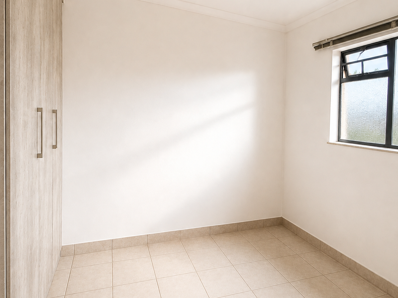 A bright, empty bedroom featuring neutral tiled flooring, built-in wooden cupboards, and a modern ceiling spotlight fixture.