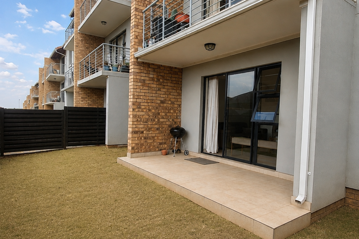 Rear view of an apartment building featuring a ground-floor tiled patio, upper-level balconies with metal railings, and sliding glass door access.