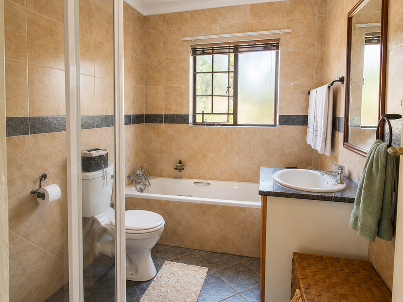 A functional bathroom featuring a shower enclosure, bathtub, vanity with basin, and neutral wall tiling.