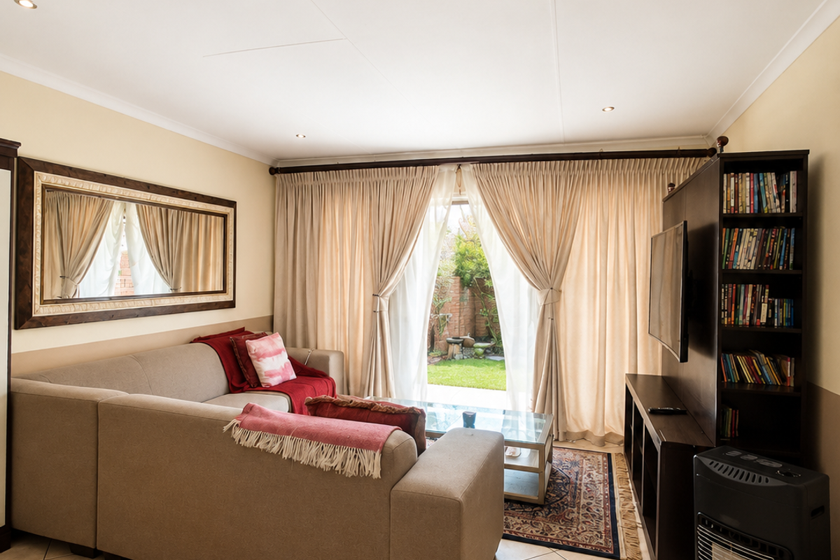 A well-maintained living room featuring tiled flooring, recessed downlighting, and direct access to the rear garden through sliding glass doors.