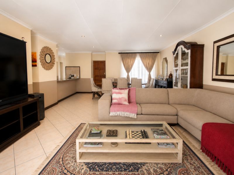Spacious open-plan living and dining area featuring tiled flooring, recessed lighting, and a breakfast counter connecting to the kitchen space.