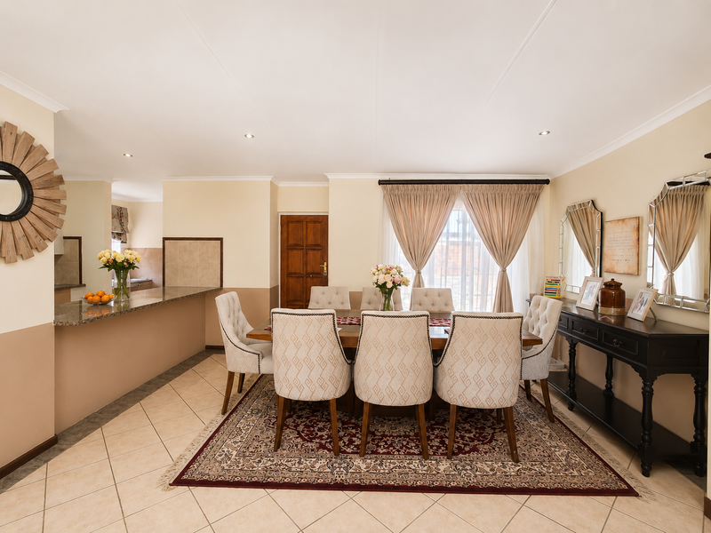 Spacious open-plan dining area featuring tiled flooring, recessed lighting, and a granite breakfast counter connecting to the kitchen.