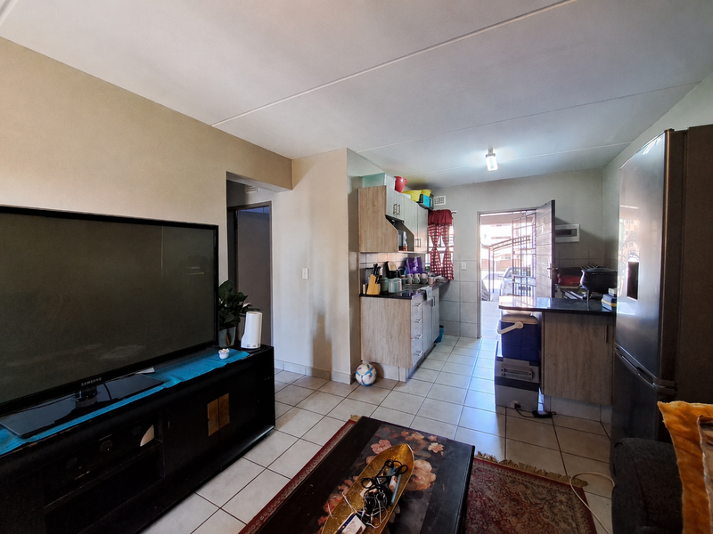 Open plan living and kitchen area featuring tiled flooring and built-in cabinetry, with direct access to an exterior entrance.