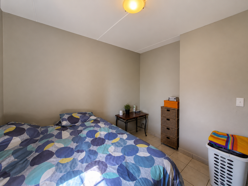 A functional bedroom featuring neutral wall tones, tiled flooring, and a central ceiling light fixture.