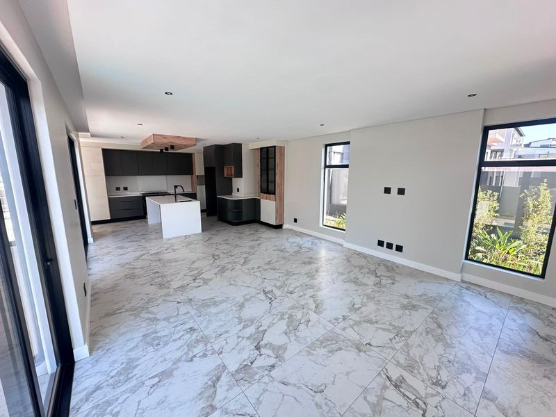 Spacious open-plan living and kitchen area featuring modern cabinetry, a central island, and high-quality marble-look floor tiles throughout.