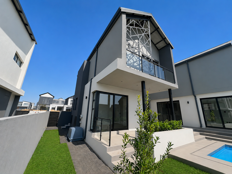 Modern double-story rear elevation featuring a swimming pool, paved patio area, and an upper-level balcony with a decorative metal screen.