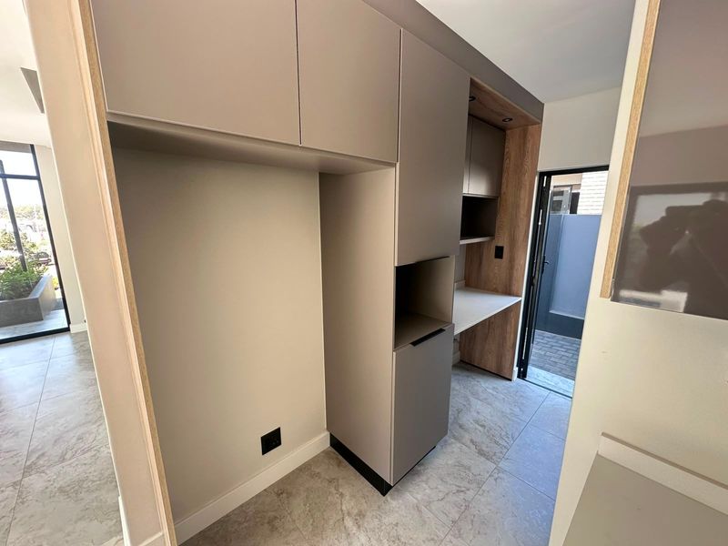 A modern, clean scullery area featuring built-in cabinetry, ample storage, and tiled flooring, providing a functional secondary prep or utility space.