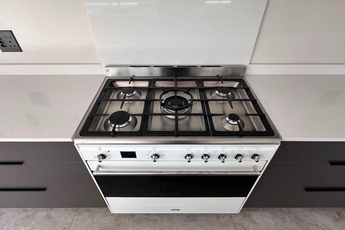 Modern kitchen featuring a high-end gas cooktop, integrated oven, sleek stone benchtops, and contemporary dark cabinetry with a clean glass splashback.