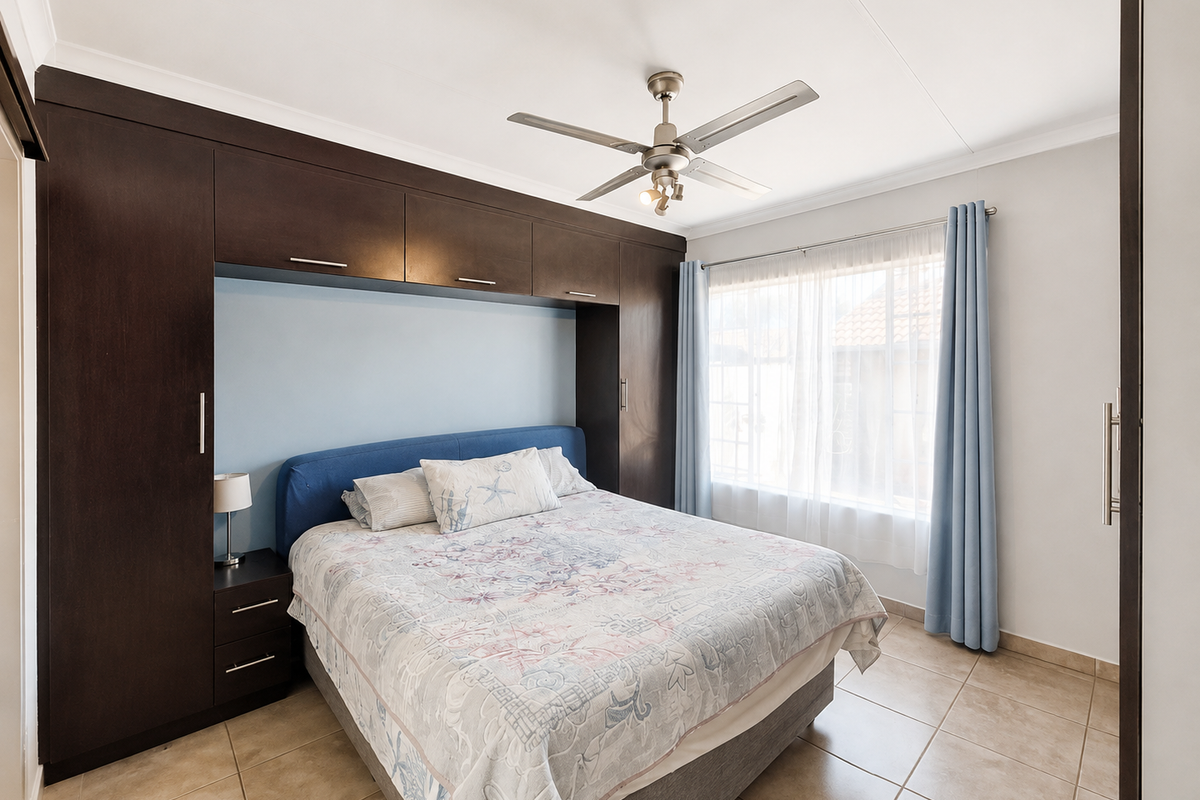 A well-maintained bedroom featuring extensive dark wood built-in cabinetry, tiled flooring, and a ceiling fan, offering a functional and organized living space.