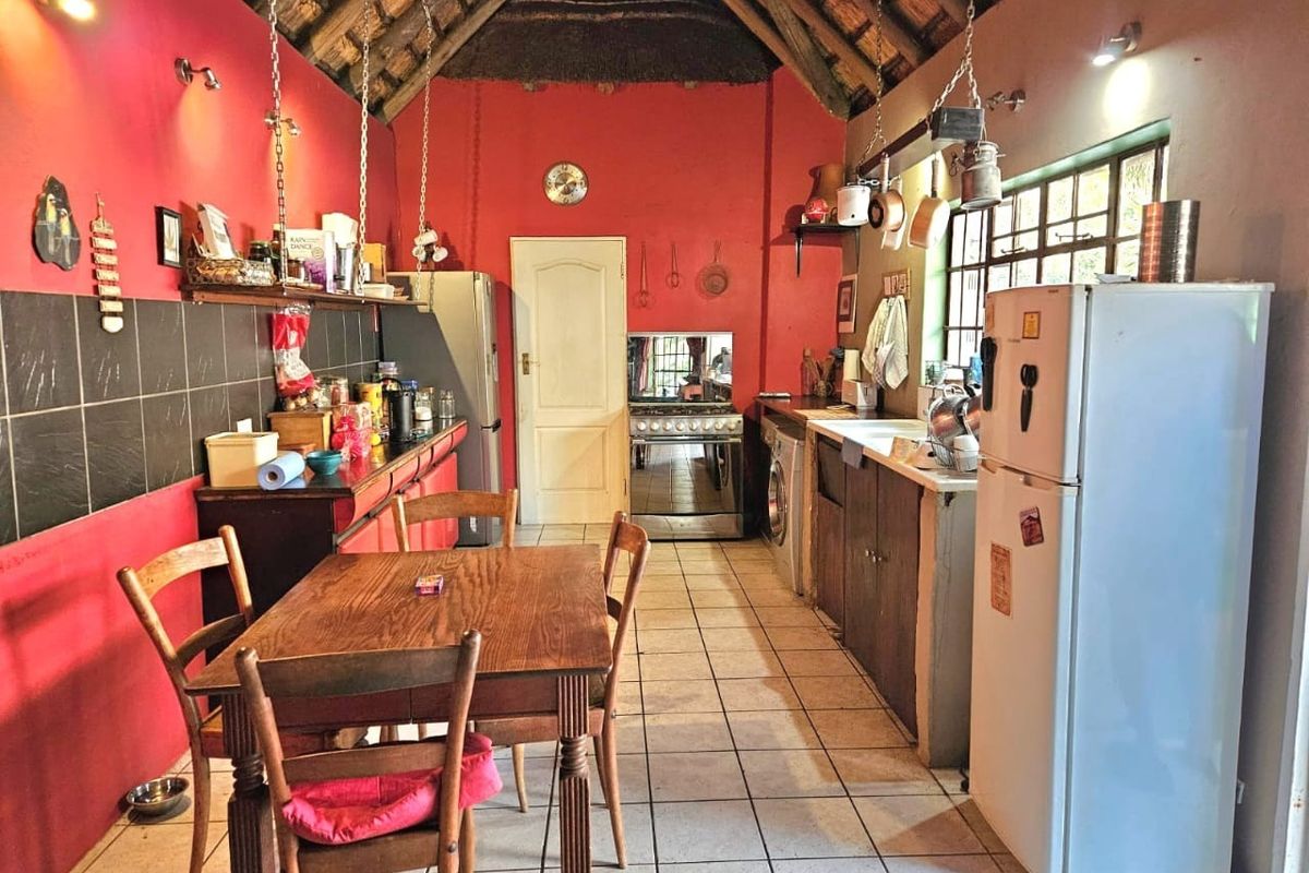 Rustic kitchen featuring a high thatched ceiling with exposed rafters, tiled flooring, gas stove, and built-in cabinetry with a double basin sink.