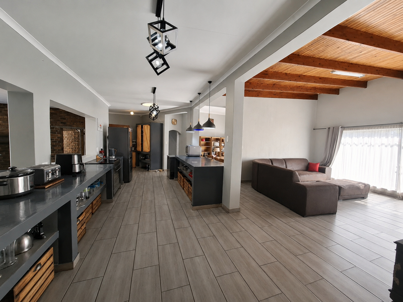 Spacious open-plan living and kitchen area featuring modern tiled floors, exposed timber ceiling beams, and a functional kitchen island with integrated cabinetry.