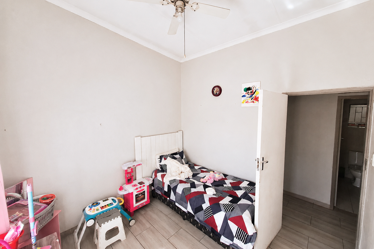 A bedroom featuring tiled flooring, a ceiling fan, and direct access to an adjoining bathroom.