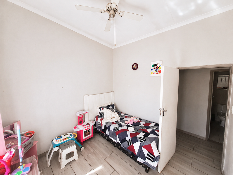 A bedroom featuring tiled flooring, a ceiling fan, and direct access to an adjoining bathroom.