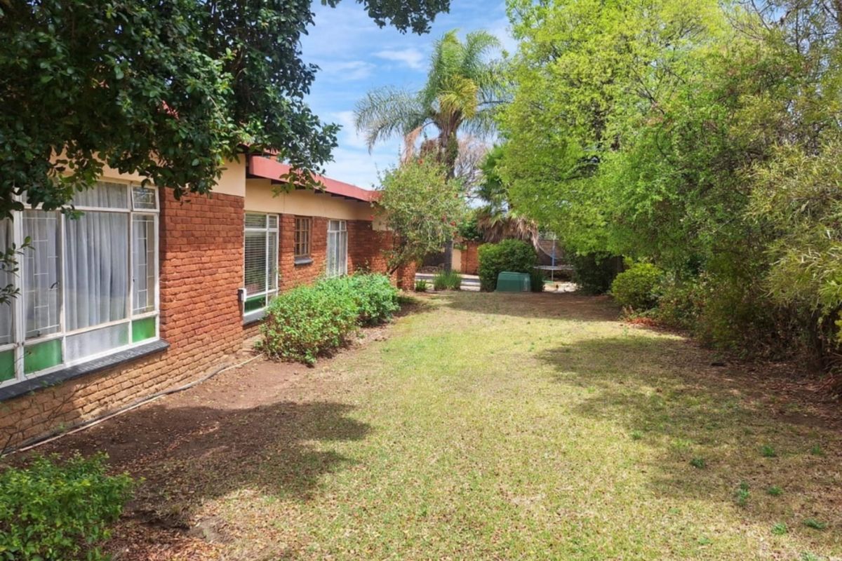 A view of the rear garden featuring an exposed brick exterior wall and established landscaping.