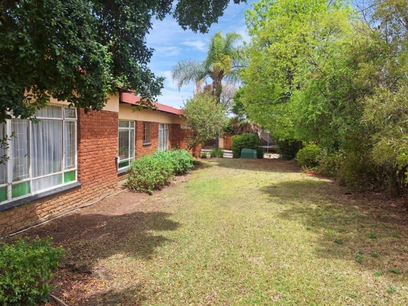 A view of the rear garden featuring an exposed brick exterior wall and established landscaping.