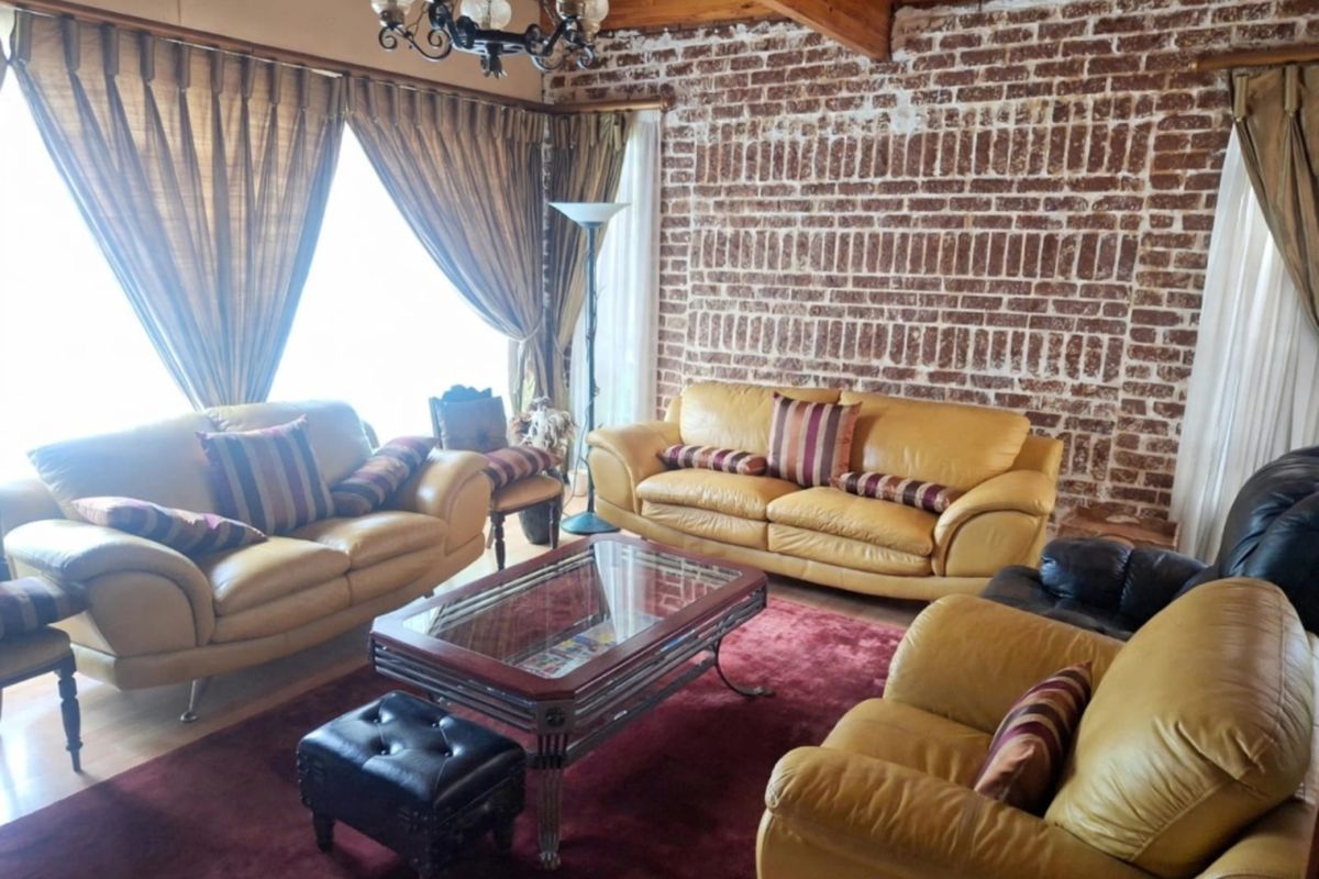 A rustic living room featuring exposed brick walls, timber ceiling beams, and hardwood flooring, creating a warm and character-filled space.