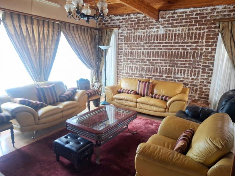 A rustic living room featuring exposed brick walls, timber ceiling beams, and hardwood flooring, creating a warm and character-filled space.