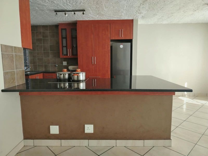 A functional kitchen featuring dark wood cabinetry, granite countertops, a breakfast bar, and tiled flooring, offering a practical layout for daily use.