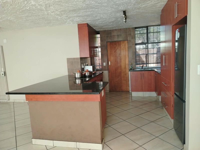 A functional kitchen featuring dark wood cabinetry, granite countertops, a breakfast bar, and tiled flooring, offering a practical layout for daily cooking and dining.