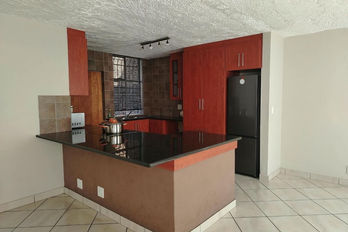 A functional kitchen featuring dark wood cabinetry, granite countertops, a breakfast bar, and tiled flooring, offering a practical layout for daily use.