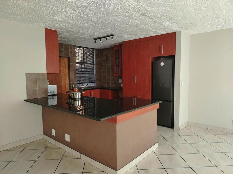 A functional kitchen featuring dark wood cabinetry, granite countertops, a breakfast bar, and tiled flooring, offering a practical layout for daily use.