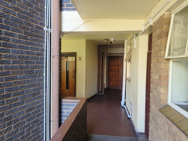 An exterior apartment hallway featuring brick walls, a security gate, and access to unit 3.