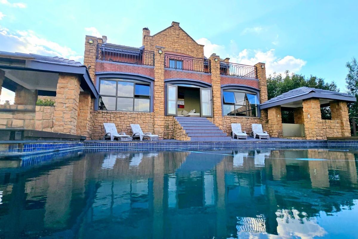 Rear elevation of the lodge featuring a swimming pool, stone-clad facade, covered patio areas, and an upper-level balcony.