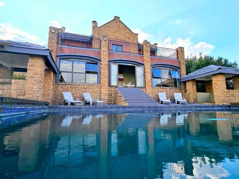 Rear elevation of the lodge featuring a swimming pool, stone-clad facade, covered patio areas, and an upper-level balcony.