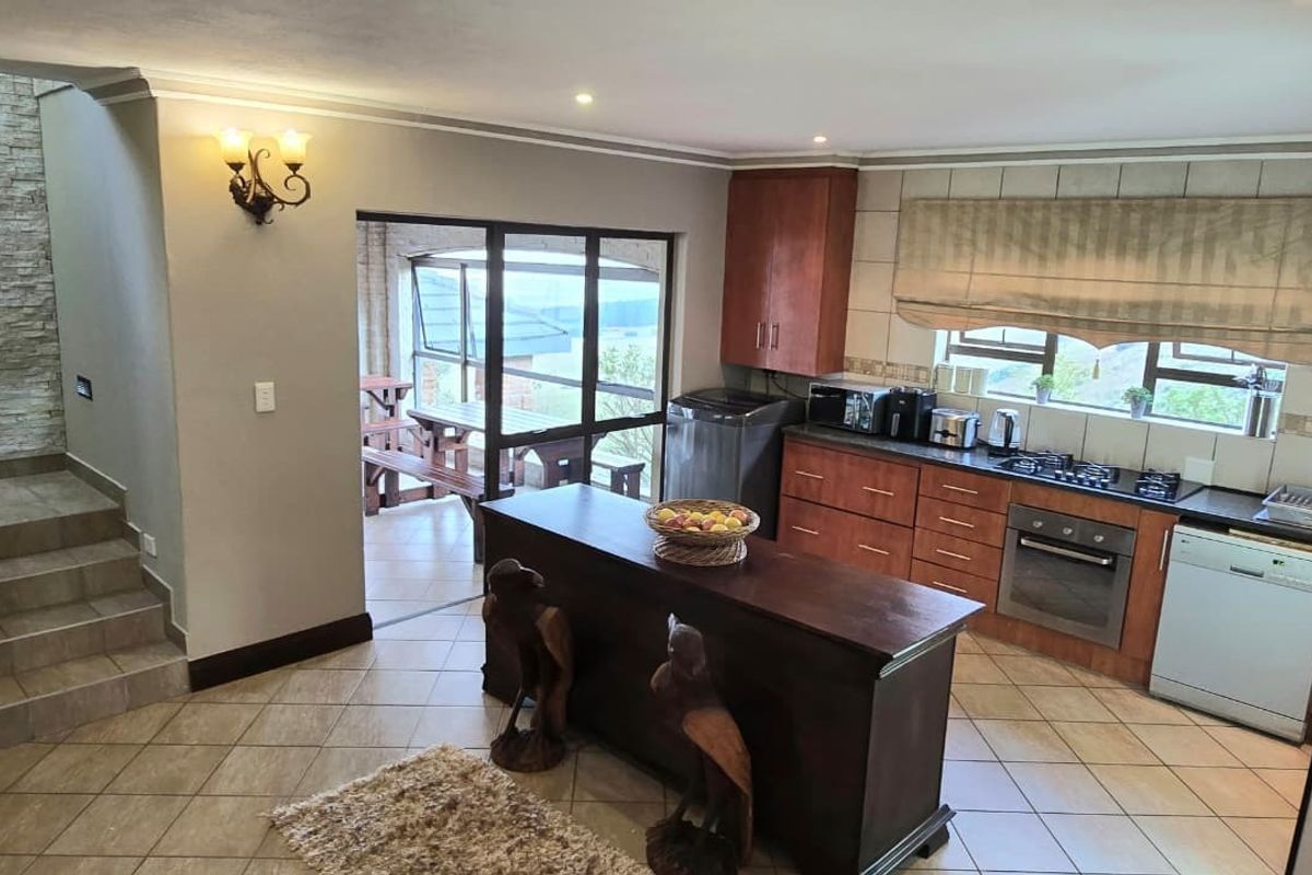 A functional kitchen featuring wooden cabinetry, built-in appliances, tiled flooring, and a stone feature wall, with direct access to an outdoor patio area.