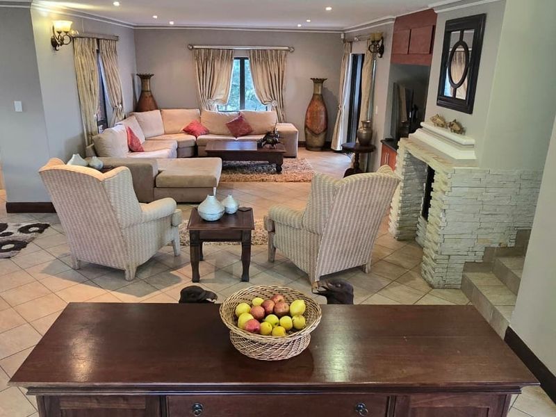 Spacious living area featuring a prominent stone-clad fireplace, tiled flooring, and recessed lighting, creating a comfortable and inviting atmosphere.
