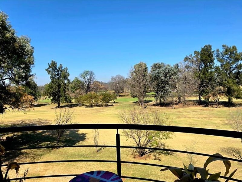 A balcony featuring a metal balustrade with an expansive, unobstructed view of the surrounding parkland and golf course.