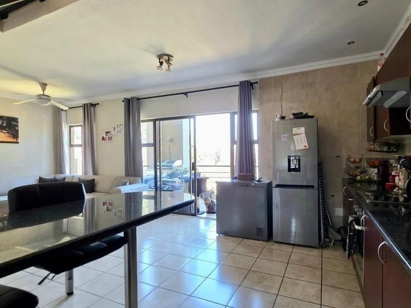 Open-plan living and kitchen area featuring granite countertops, tiled flooring, and sliding door access to the patio.