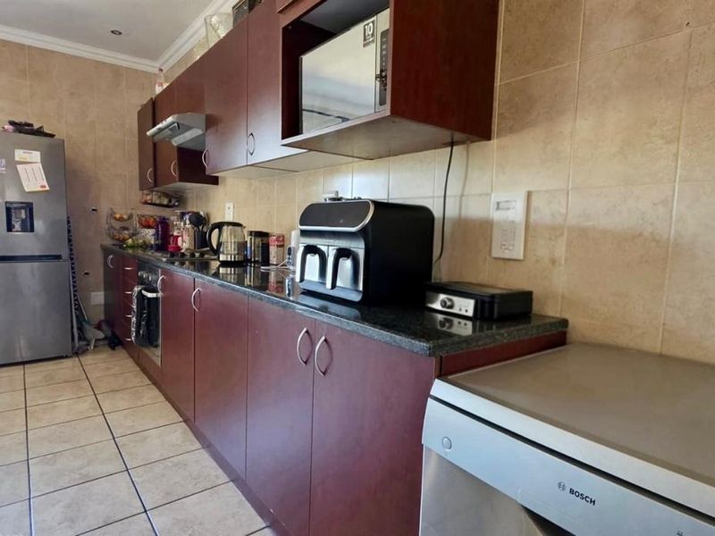 A functional kitchen featuring dark wood cabinetry, granite countertops, tiled backsplash, and integrated appliances, offering a practical layout for daily meal preparation.
