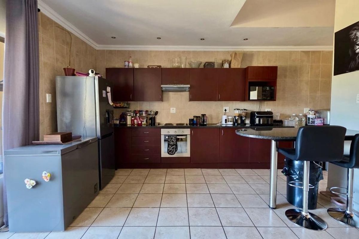 A functional kitchen featuring dark wood cabinetry, built-in oven and hob, tiled backsplash, and tiled flooring, offering a practical layout for daily use.