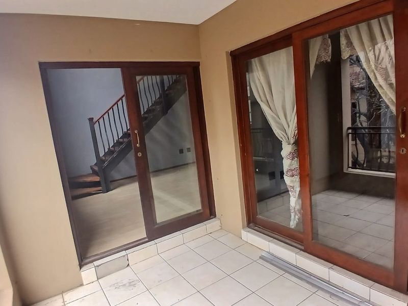 A covered balcony featuring tiled flooring, metal balustrades, and large sliding glass doors providing access to the interior living space.