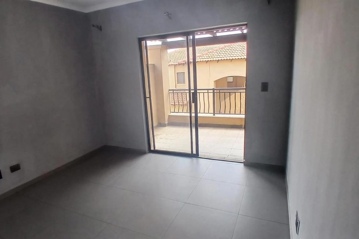 An empty bedroom featuring tiled flooring and a sliding glass door providing access to a private balcony.
