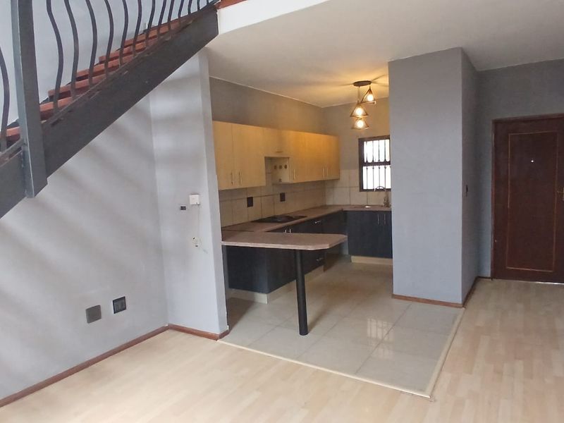 Open plan living area featuring a kitchen with built-in cabinetry, breakfast bar, and a staircase leading to the upper level.
