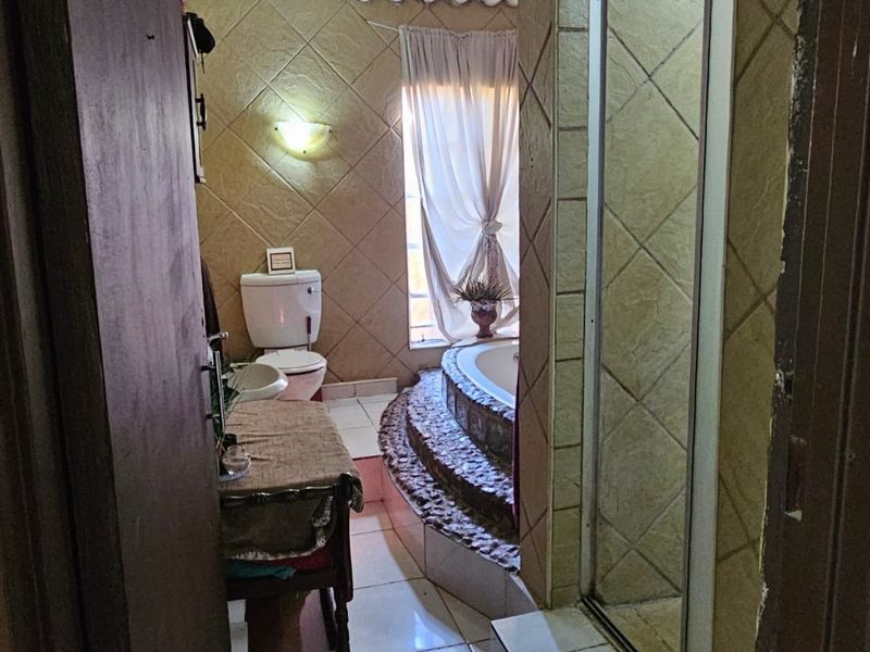 A dated bathroom featuring a built-in bathtub with stone-tiled steps, a separate shower enclosure, and ceramic floor tiling.