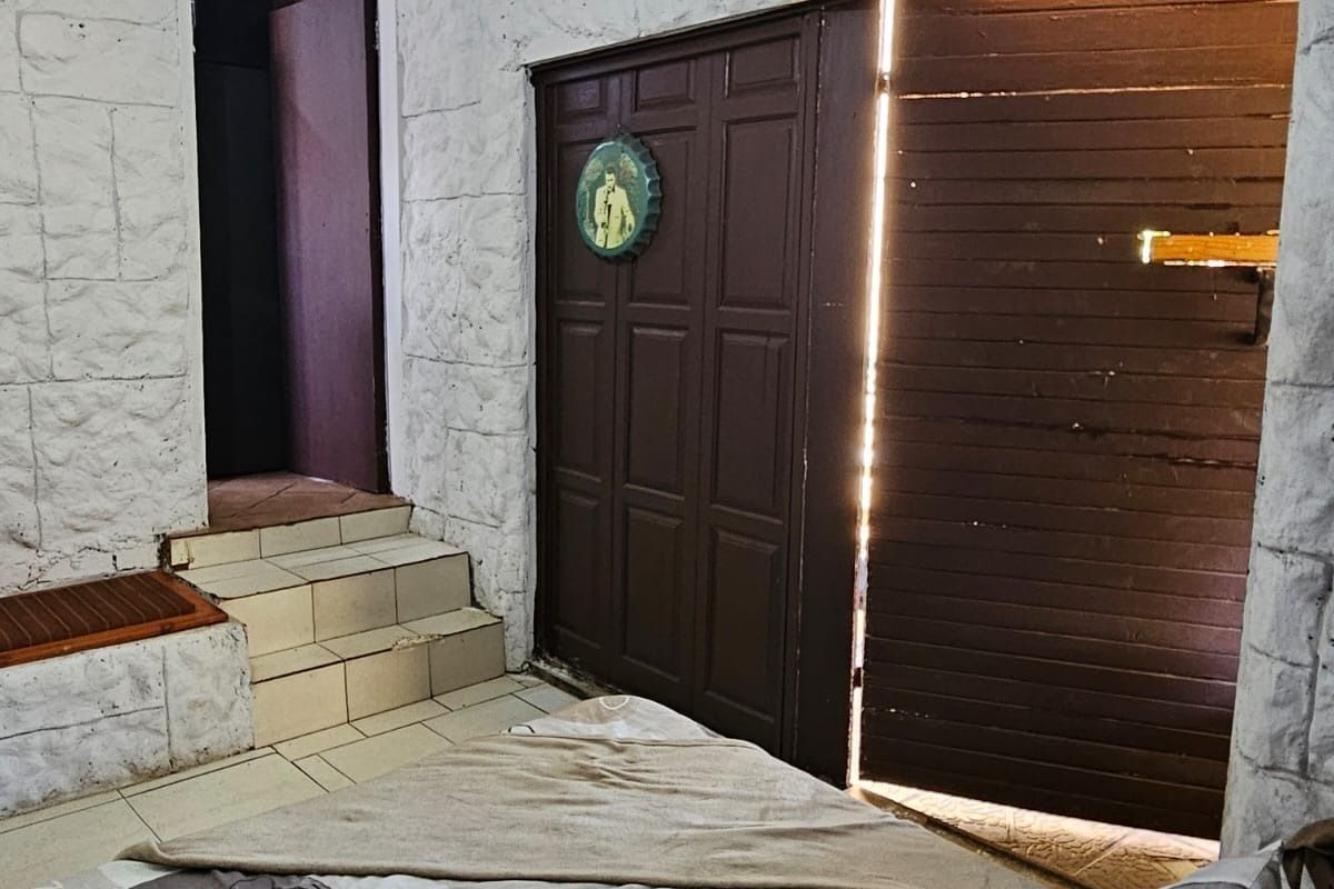 A bedroom featuring textured stone-effect wall finishes, tiled steps leading to an adjacent area, and a timber door opening to the exterior.