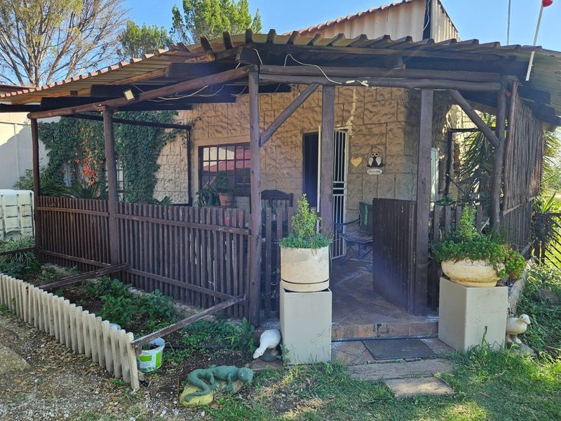 A rustic covered patio area featuring timber structural elements, stone-clad walls, and tiled flooring, providing a sheltered outdoor space.