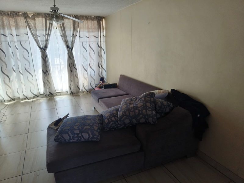 Living room featuring tiled flooring, a ceiling fan, and large sliding glass doors providing natural light.