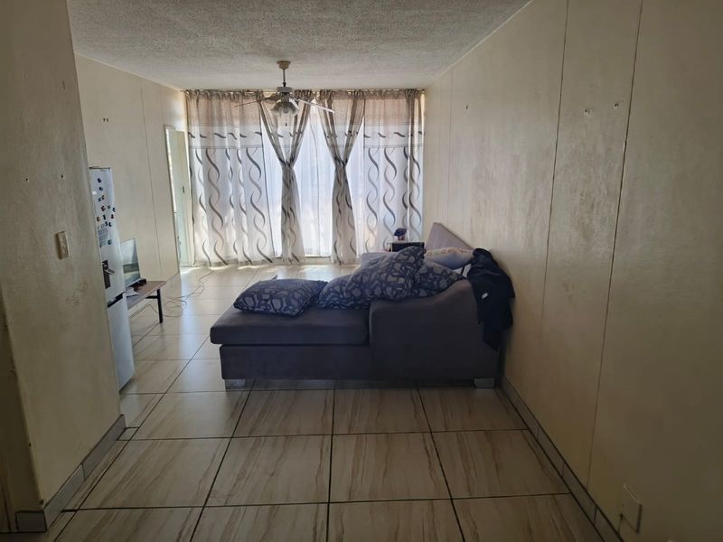 A living room area featuring tiled flooring, a ceiling fan, and a large sliding glass door providing natural light.