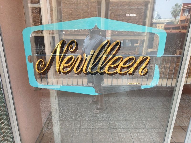 A balcony area featuring tiled flooring and a metal safety railing, currently obstructed by a large signage sticker on the glass door.