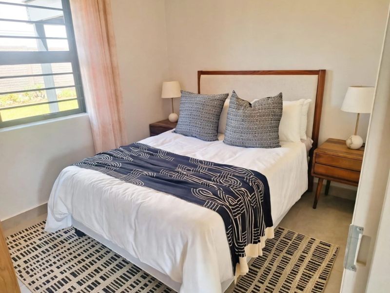 A well-maintained bedroom featuring neutral walls and an aluminium-framed window, providing a bright and comfortable living space.
