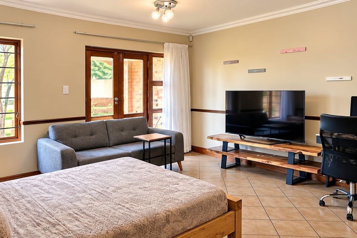 Spacious bedroom featuring tiled flooring, large windows with security bars, and direct access to an outdoor area through wooden doors.
