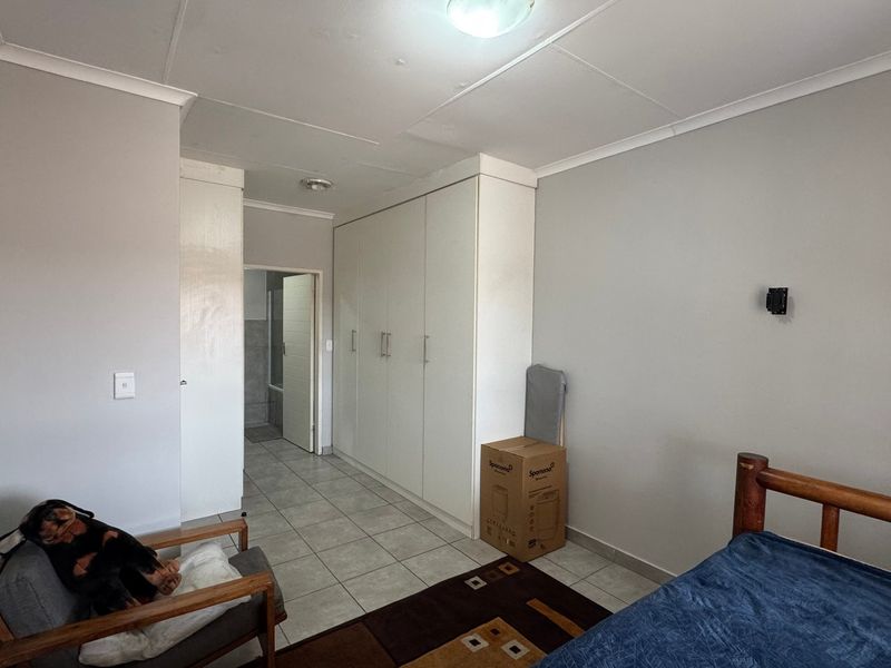 Bedroom featuring tiled flooring, built-in cupboards, and direct access to an en-suite bathroom.