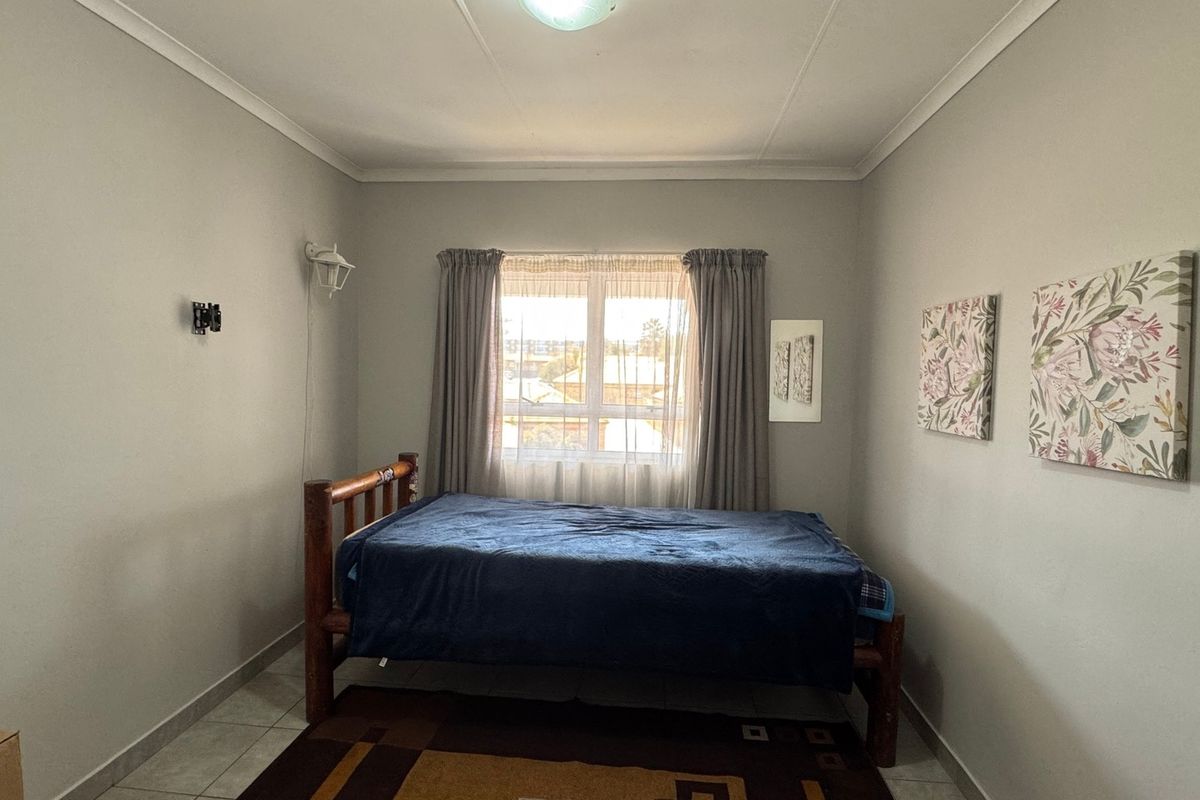A functional bedroom featuring tiled flooring, neutral wall finishes, and a window providing natural light.