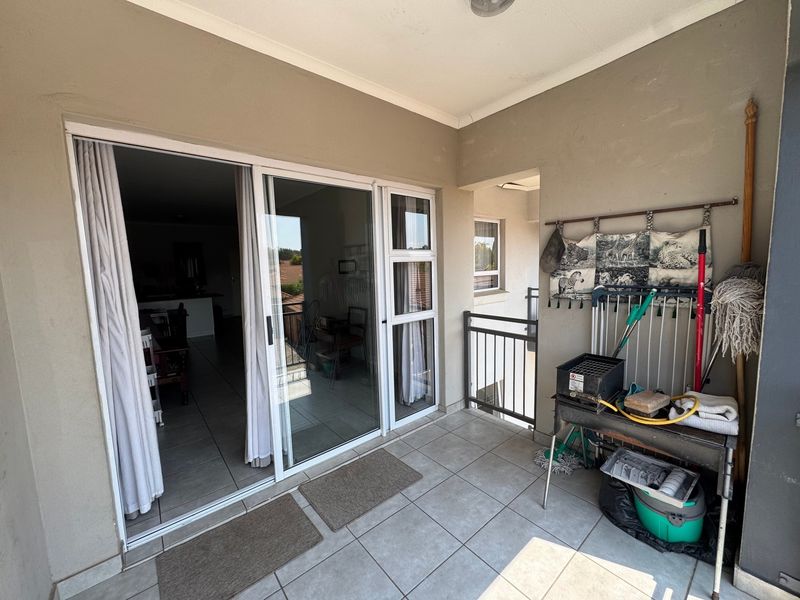 A covered balcony featuring tiled flooring, a metal balustrade, and sliding glass door access to the interior living area.