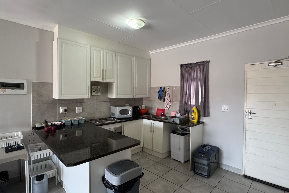 A functional kitchen featuring granite countertops, white cabinetry, tiled backsplash, and built-in cooking appliances, offering a clean and practical workspace.