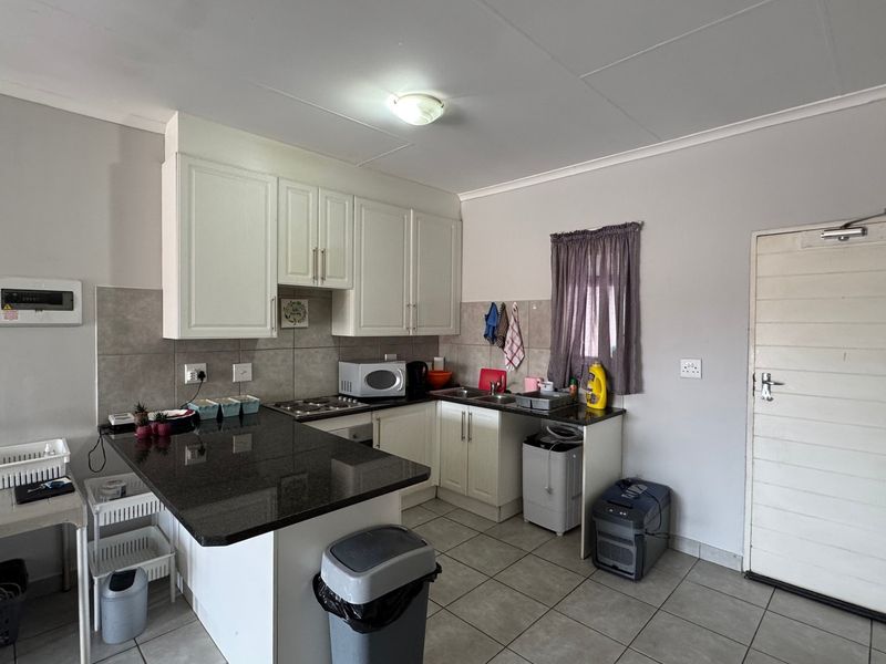 A functional kitchen featuring granite countertops, white cabinetry, tiled backsplash, and built-in cooking appliances, offering a clean and practical workspace.